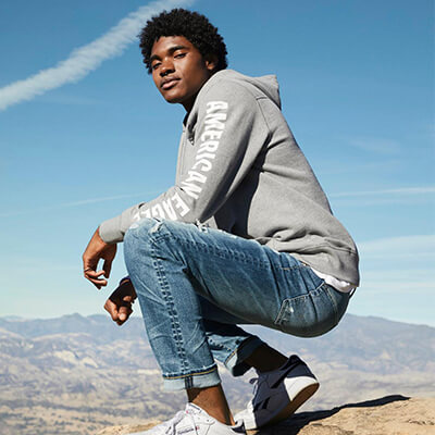 Man in gray sweater and jeans posing on top of a hill